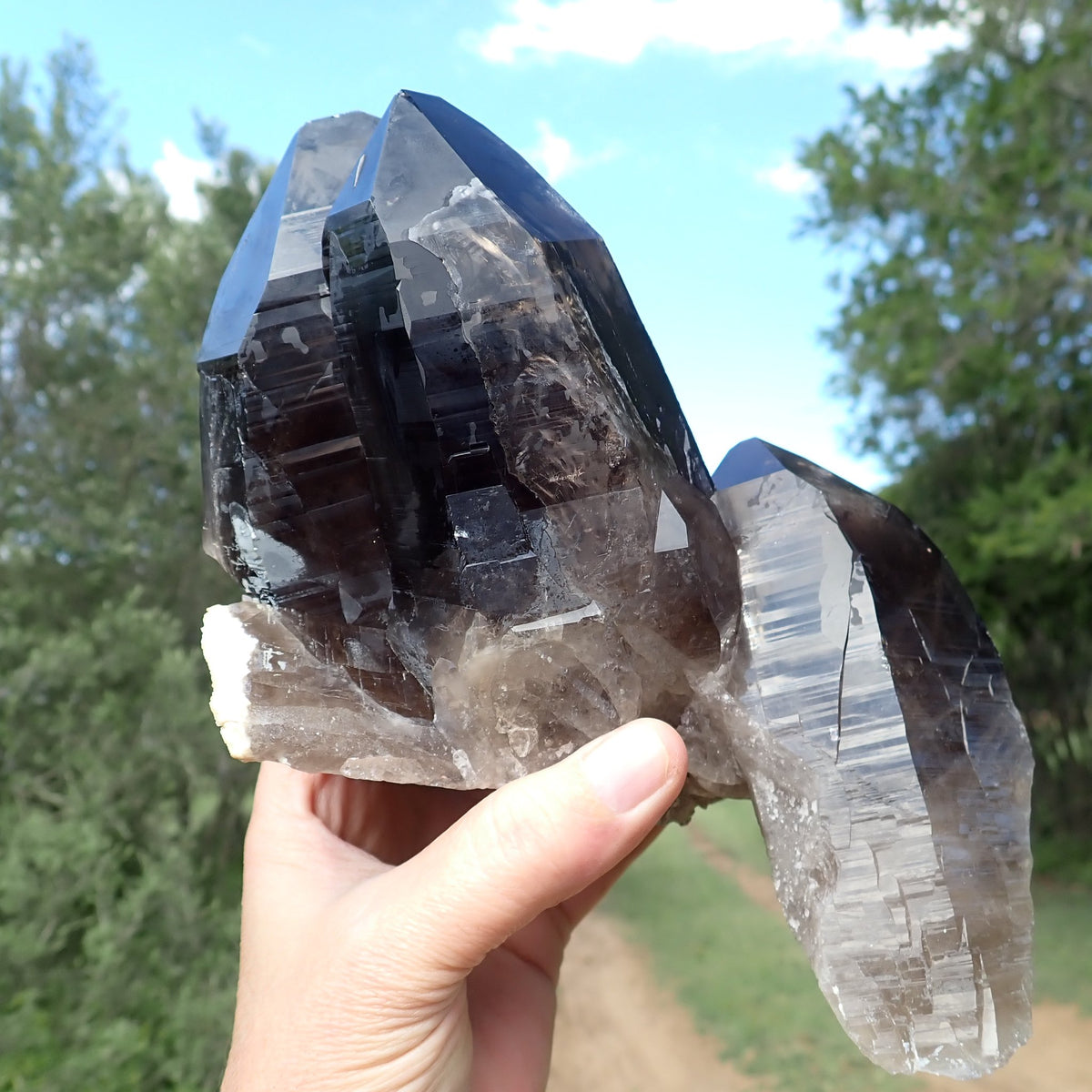 Smoky quartz crystal cluster from Zomba, Malawi, front view showing intergrown points, horizontal growth striations and translucent areas near the base.