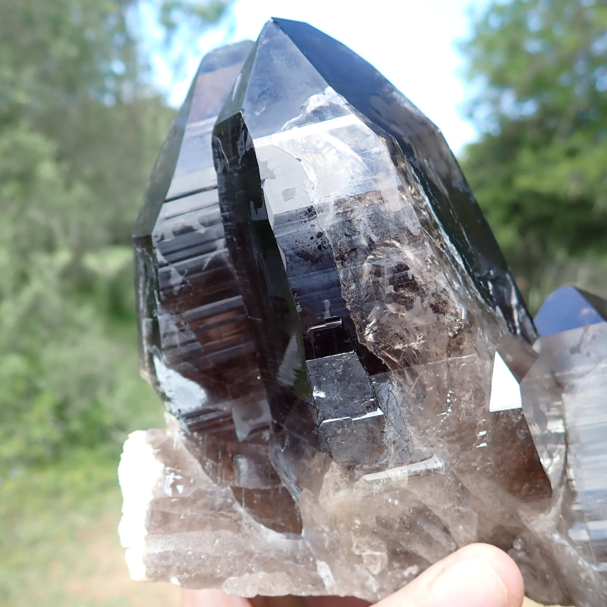 Smoky quartz from Zomba, Malawi, close-up of stepped crystal surfaces, horizontal growth striations and lighter translucent areas.