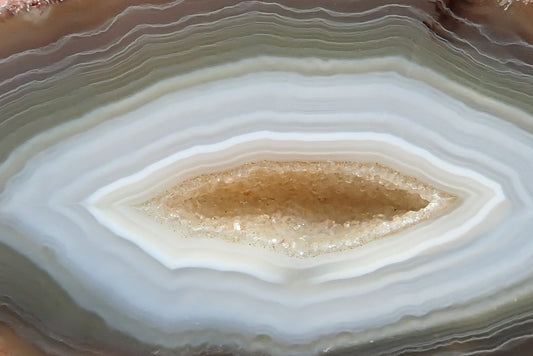 South African agate 87 mm – close-up, lens-shaped drusy vug, scalloped concentric banding, cream and blue-grey