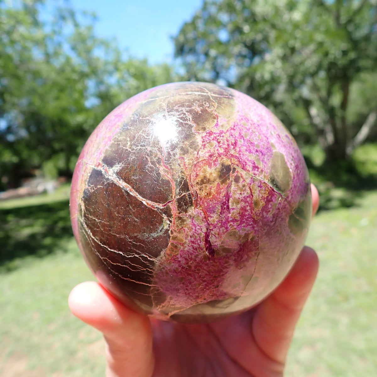Stichtite with Serpentine sphere showing broad brown patches and fine pale veining alongside pink-purple intergrowths.