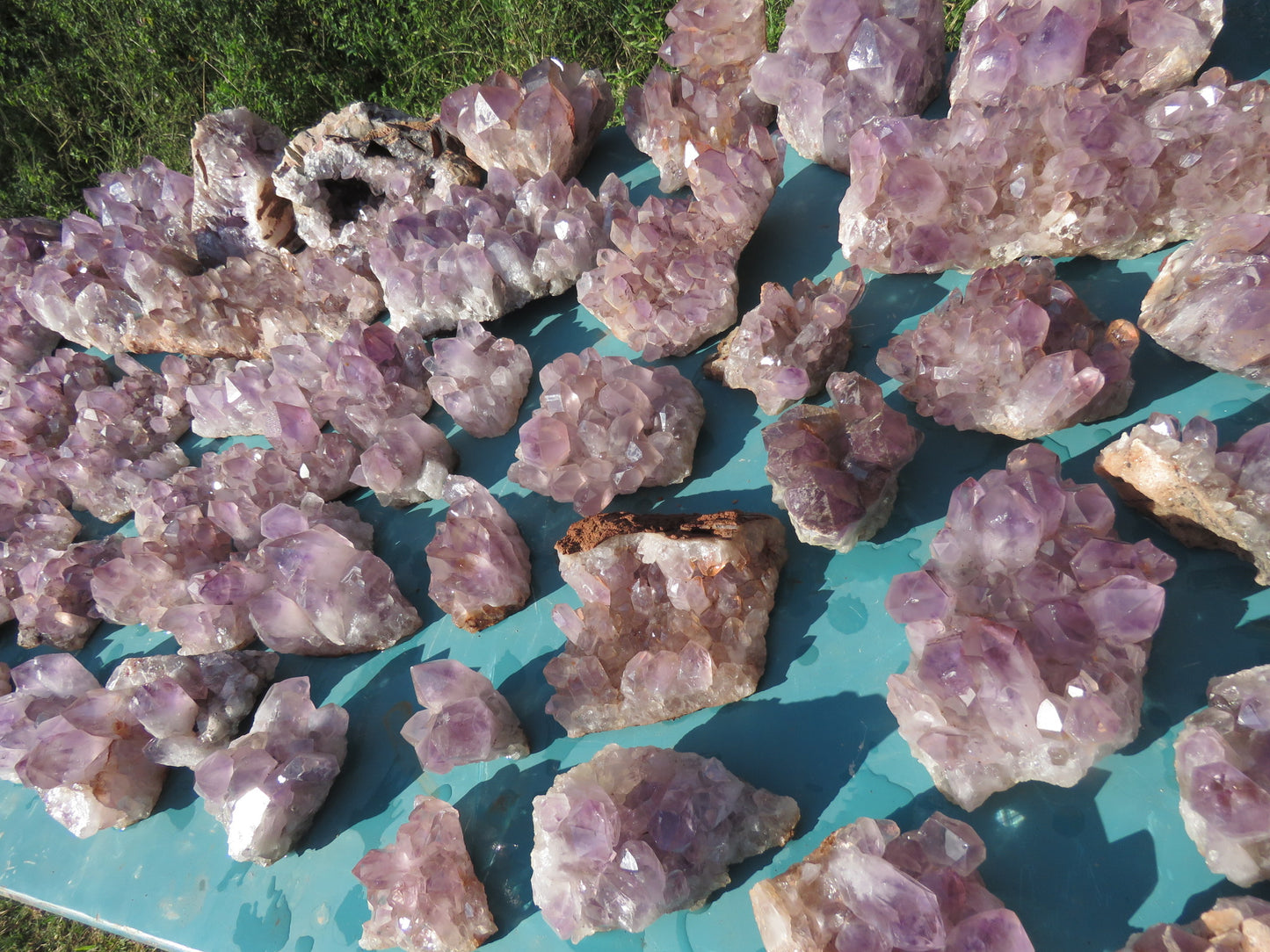 Wholesale Mumbwa amethyst Zambia – bulk lot close-up showing dense multi-point cluster formations, soft pink-violet hues, iron-stained matrix bases, natural condition | SKU MUMkg