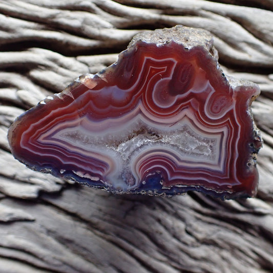 Polished Malawi agate from Ngabu region with flow channel and fortification banding in deep reds, crystalline centre