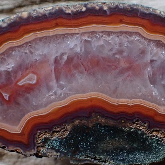 close-up of malawi agate with lovely salmon and red banding with a crystalline centre and two small floaters