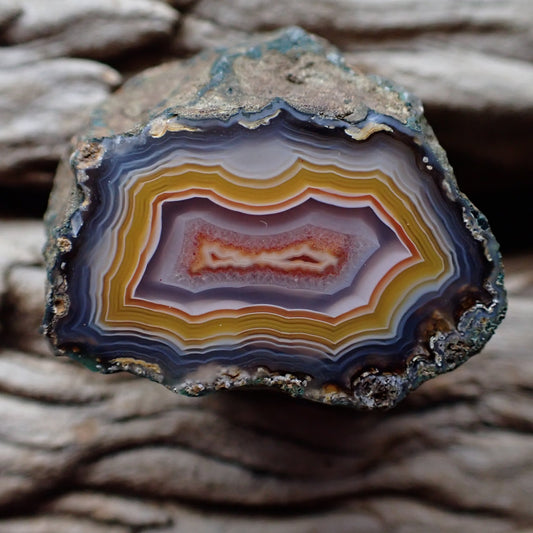 Polished Malawi agate from Ngabu region with absolutely stunning grey and yellow banding moving into an almost purple colour, with an orange double chambered floater in the crystalline centre