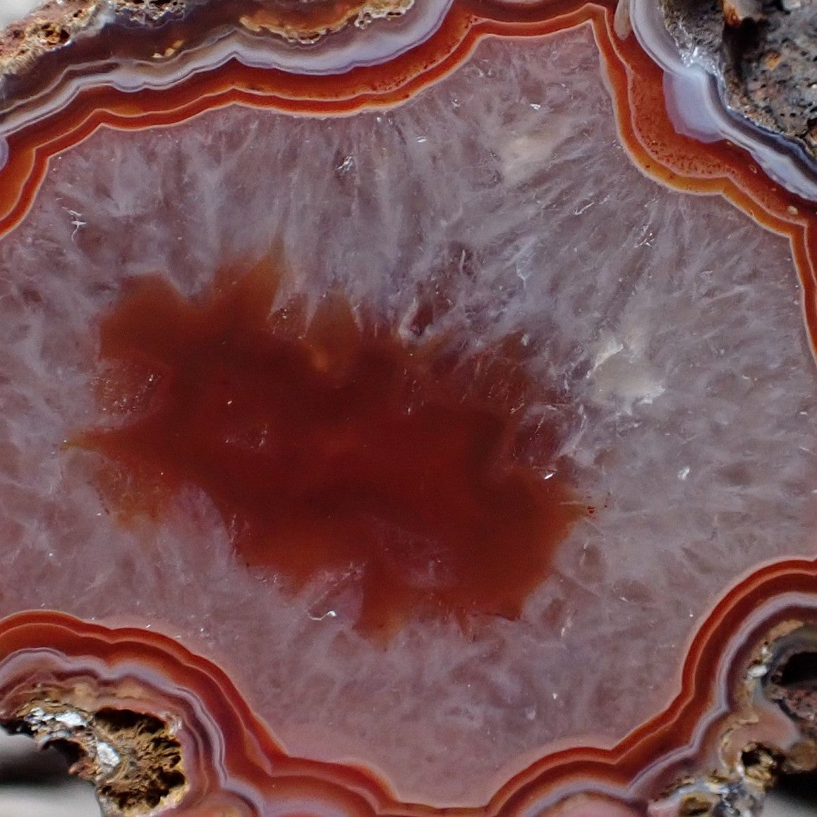 Close-up of a Malawi agate with striking bold red/orange banding around a large crystalline centre with a red floater