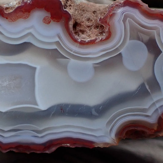 Close-up of Malawi agate 58 mm – scalloped ghost banding in blue-grey and white chalcedony with circular chalcedony forms and sard-red upper zone detail | SKU 000358