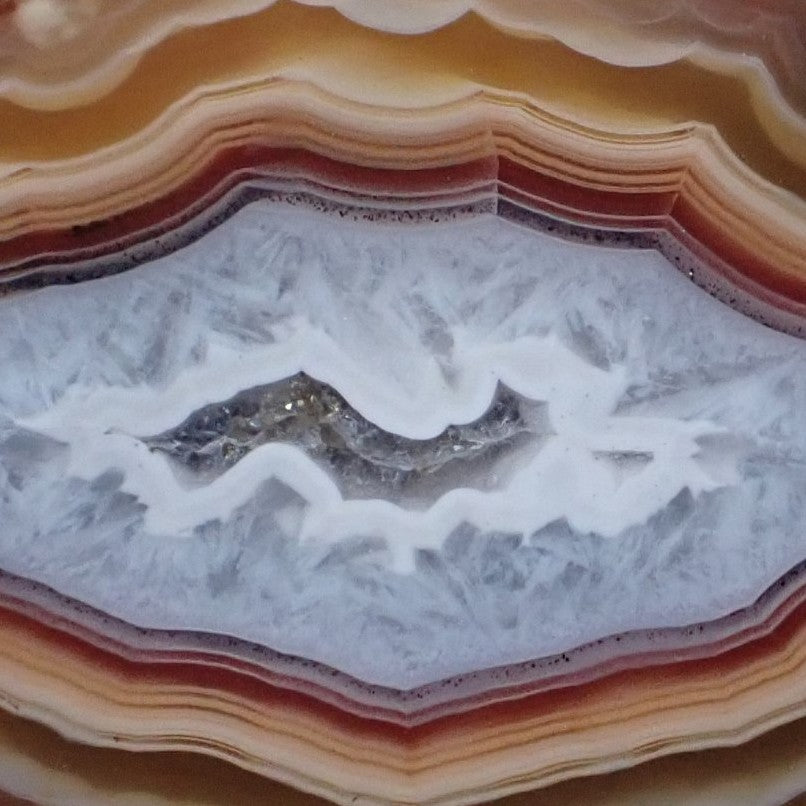 Close-up of Malawi agate 60 mm – agate floater with smooth micro-crystalline quartz interior within pale blue-grey chalcedony field, scalloped sard-red inner band detail | SKU 000367
