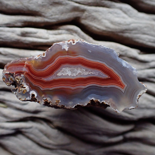 Polished Malawi agate from the Ngabu region with striking grey outer going into tight red banding around a crystalline centre exiting into a second chamber and out a flow channel