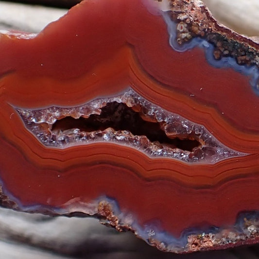 Close-up of a Malawi candy agate with purple red and orange banding surrounding its drusy centre