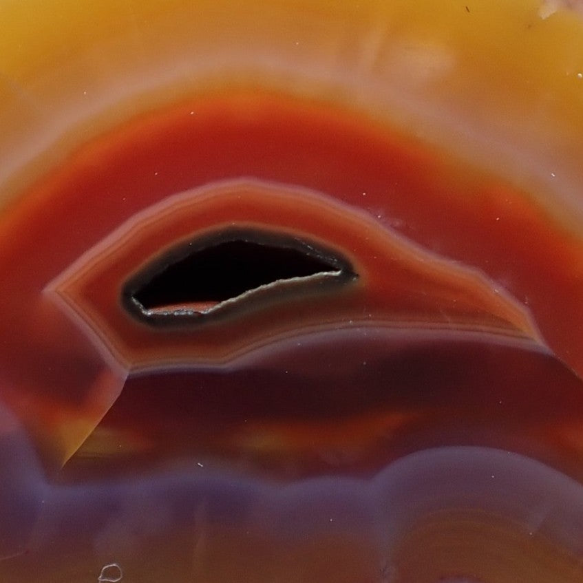 Vug Malawi agate 45 mm – detail of open vug cavity and concave banding, warm-cool colour contrast, hand-polished finish | SKU 000396