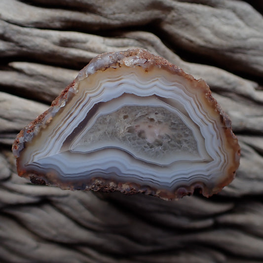 Polished Malawi agate from the Ngabu region with muted pastel colours around a crystalline centre with a floater