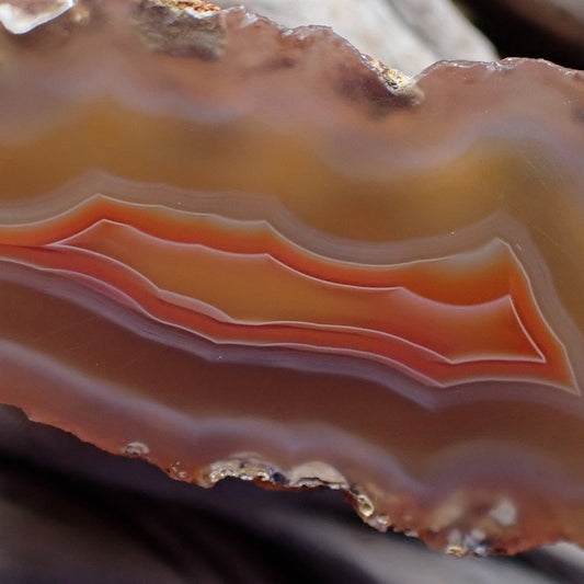 Close-up of a layered malawi agate stone with orange and brown hues.