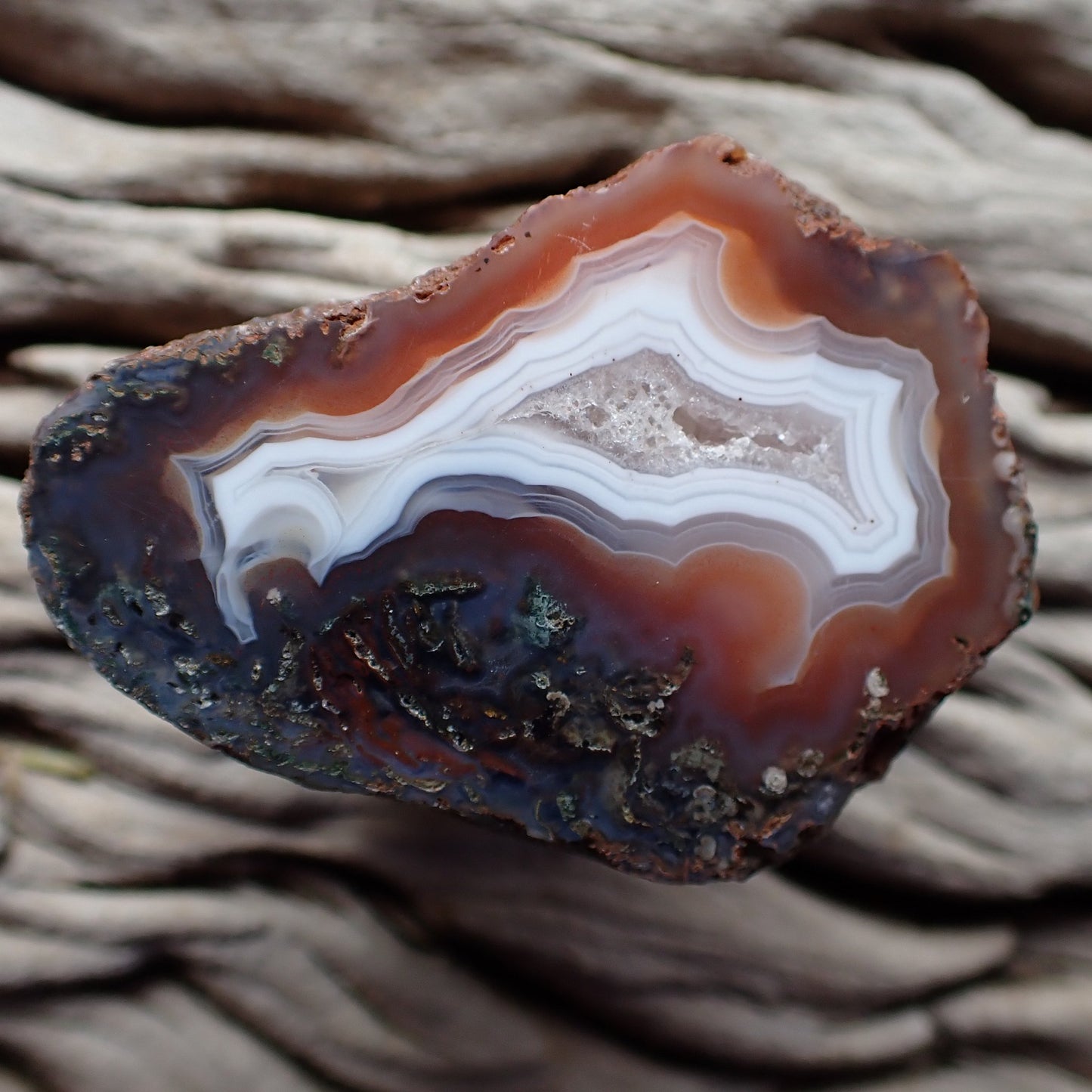 Polished Malawi agate from the Ngabu region with a crystalline centre banded with white surrounded by orange and purple with moss agate