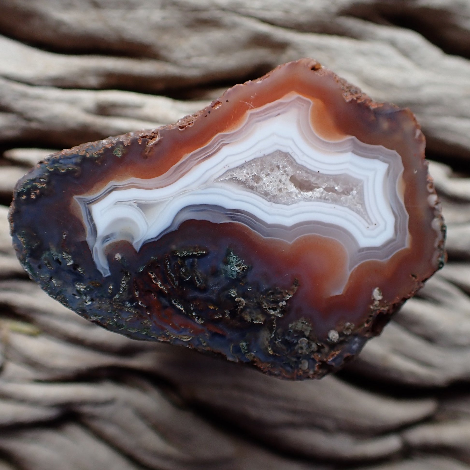Polished Malawi agate from the Ngabu region with a crystalline centre banded with white surrounded by orange and purple with moss agate