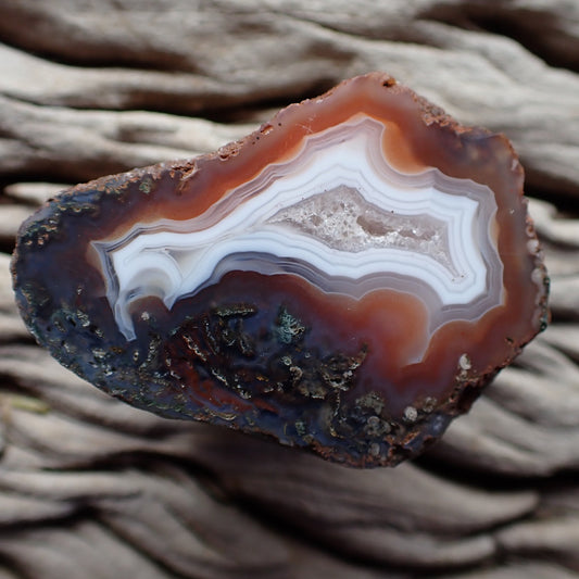 Polished Malawi agate from the Ngabu region with a crystalline centre banded with white surrounded by orange and purple with moss agate