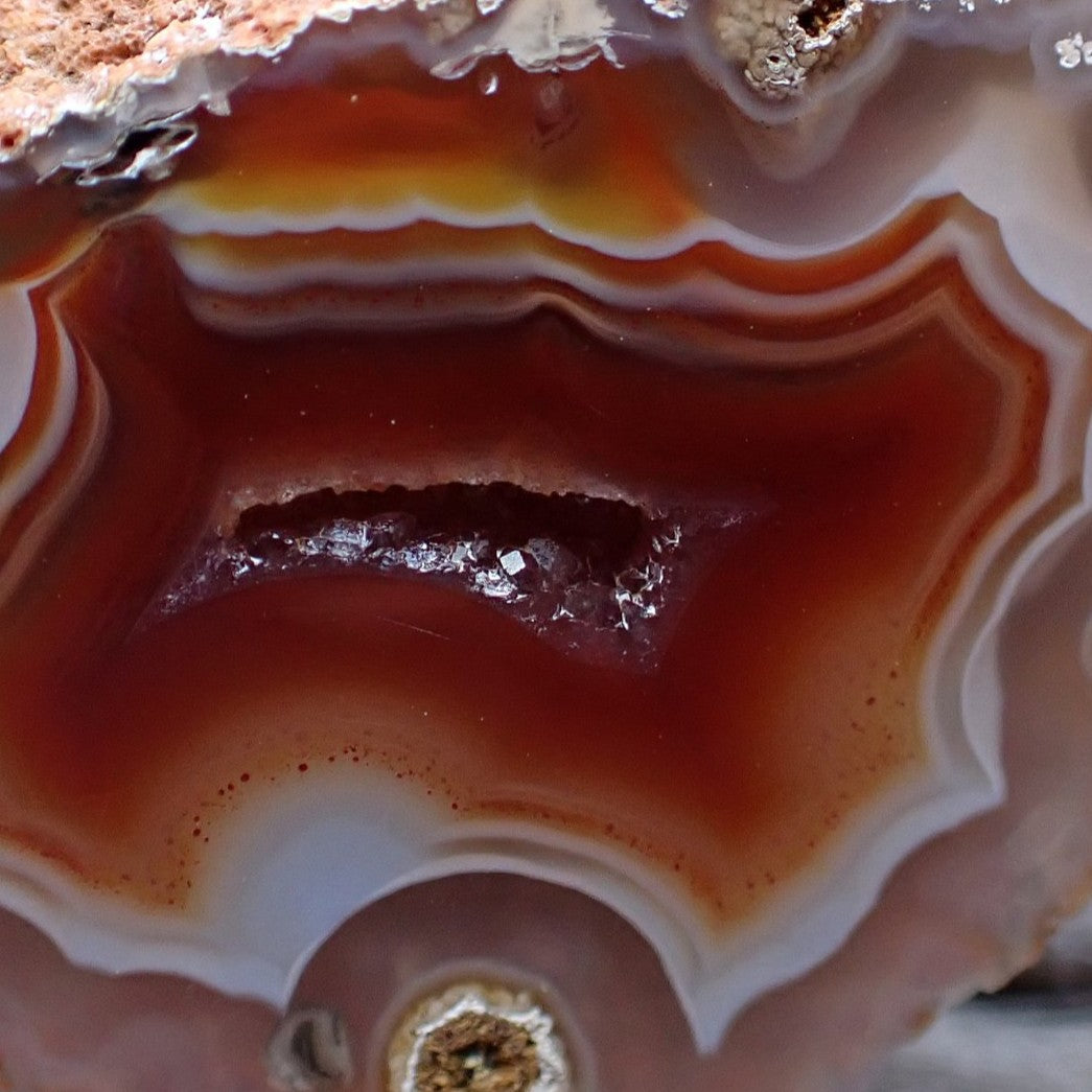 Close-up of a malawi ngabu agate stone with red, orange, and white colors and a druzi centre