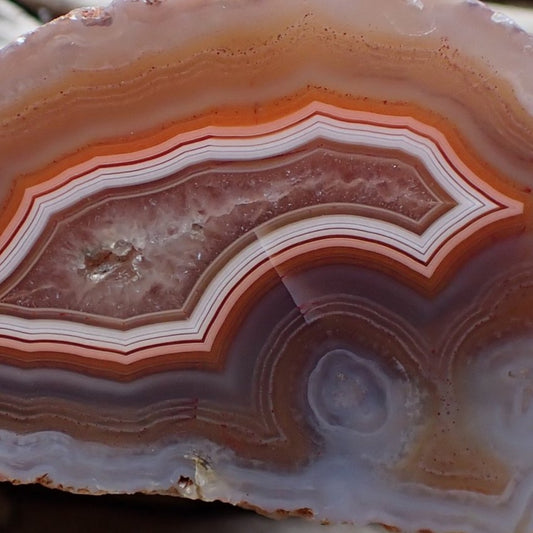 Close-up of a layered malawi agate stone with orange and pink hues.