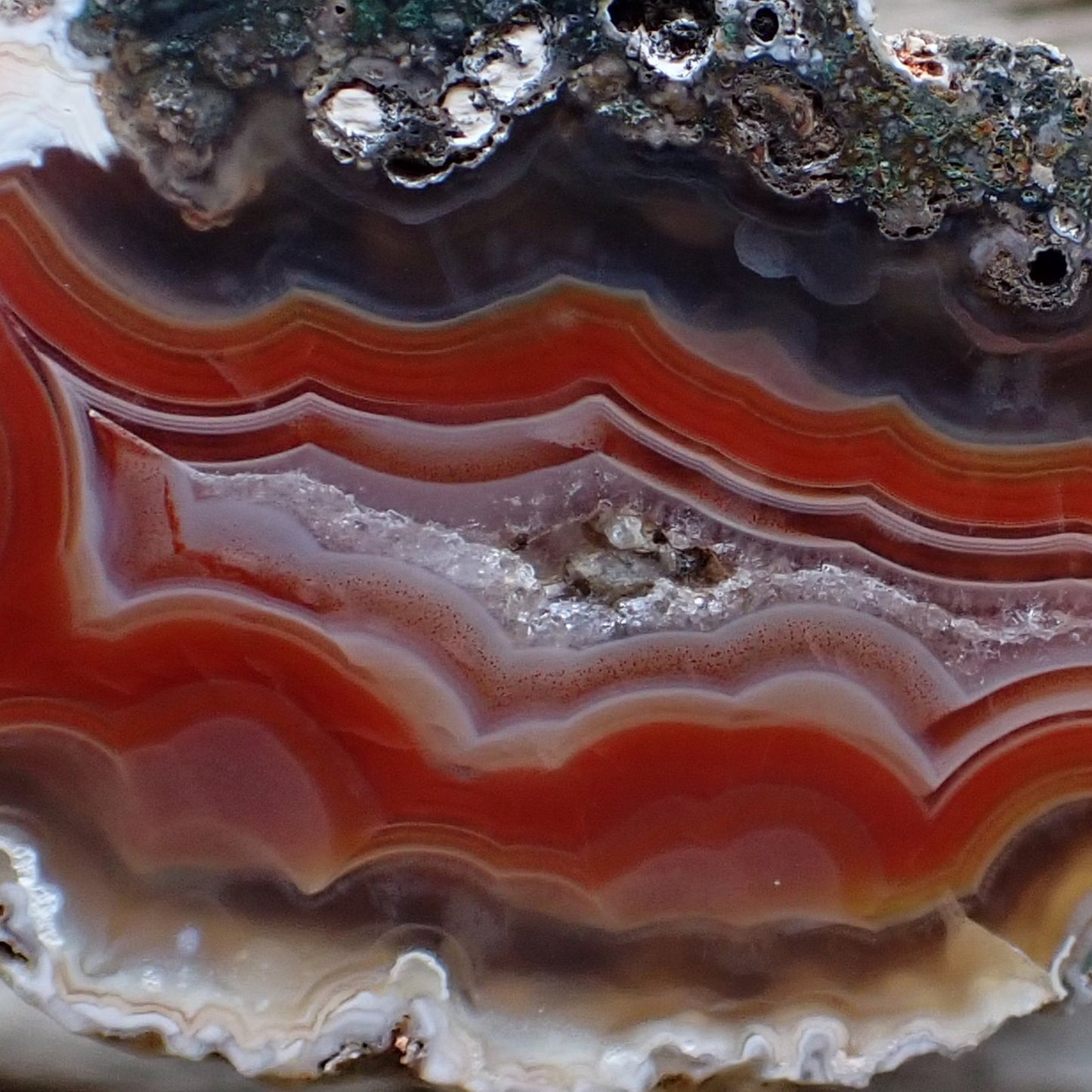Close up of a polished malawi agate showing chromatism and vibrant banding around the crystalline centre