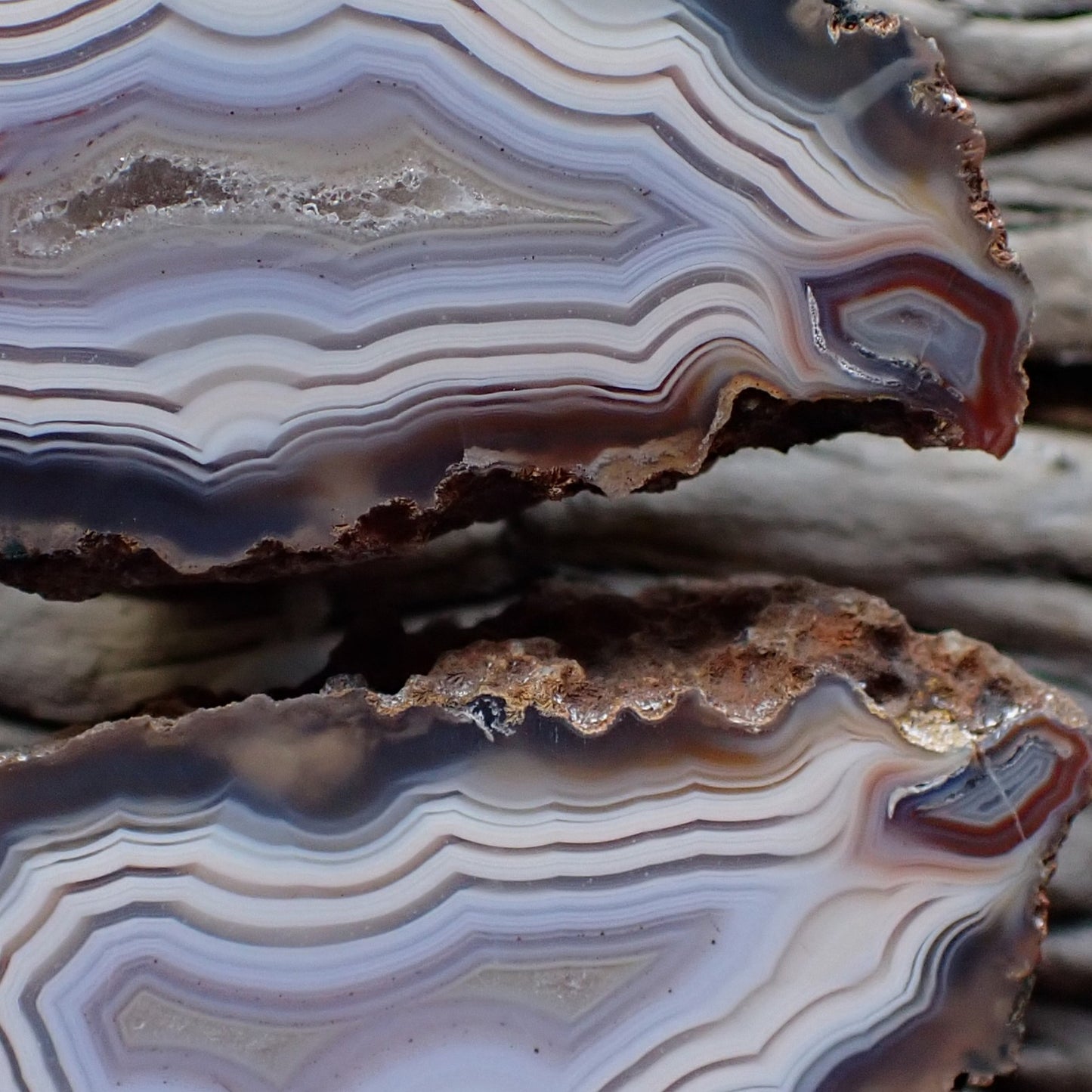close-up of a matching pair of Malawi ngabu agates with fortification banding in swirls of cream white and grey-blue going into a crystalline centre, both have matching flow channels