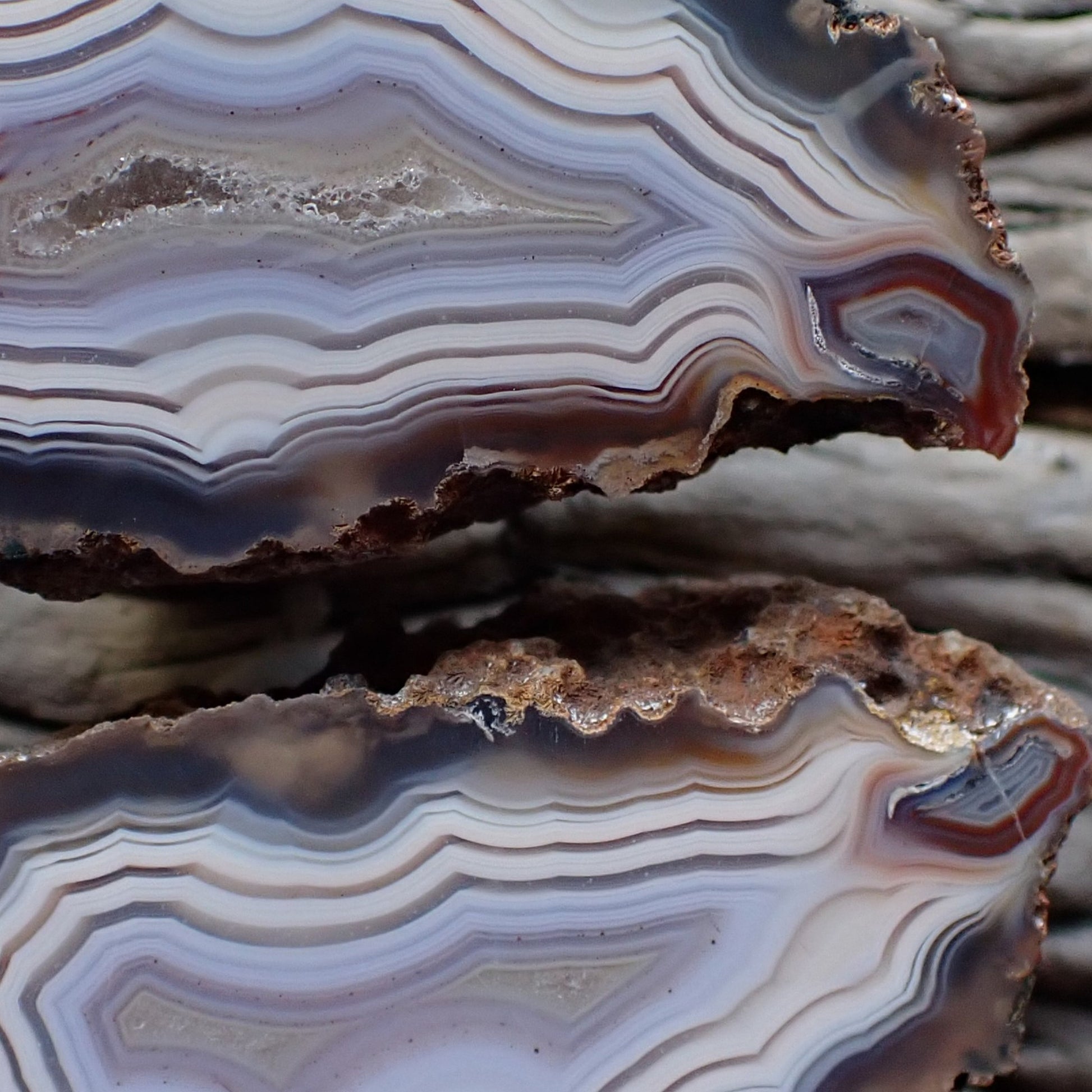 close-up of a matching pair of Malawi ngabu agates with fortification banding in swirls of cream white and grey-blue going into a crystalline centre, both have matching flow channels