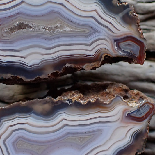 close-up of a matching pair of Malawi ngabu agates with fortification banding in swirls of cream white and grey-blue going into a crystalline centre, both have matching flow channels