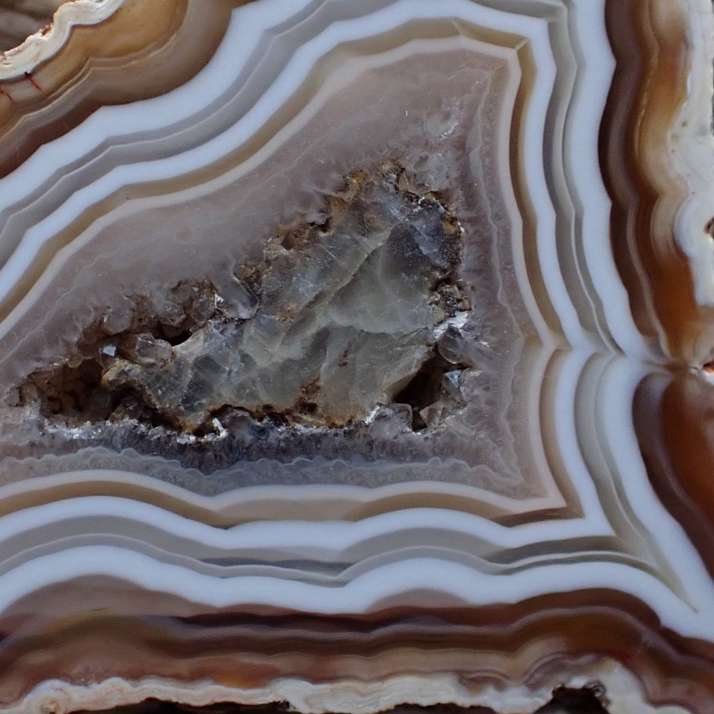 Close up of a Ngabu Malawi agate with earhty tones and ghost banding around a calcite centre