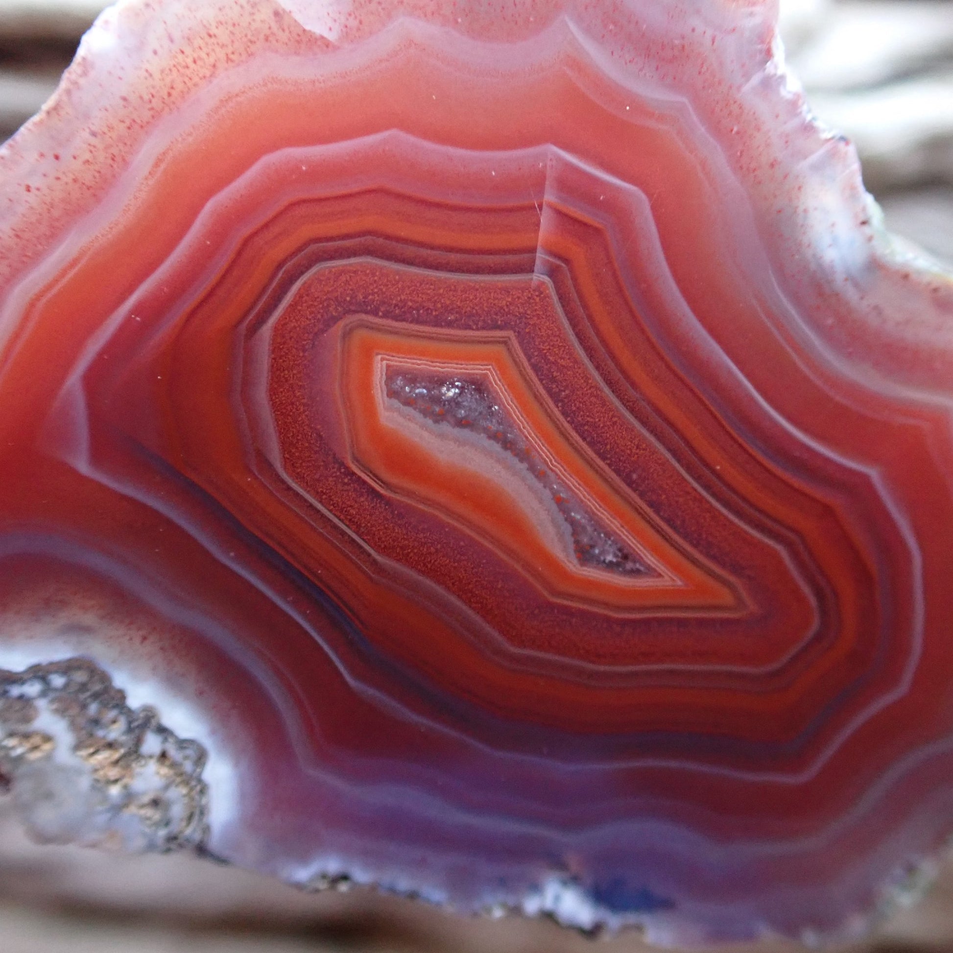 Close-up of a red and white banded Malawi agate with an orange band around a crystalline centre