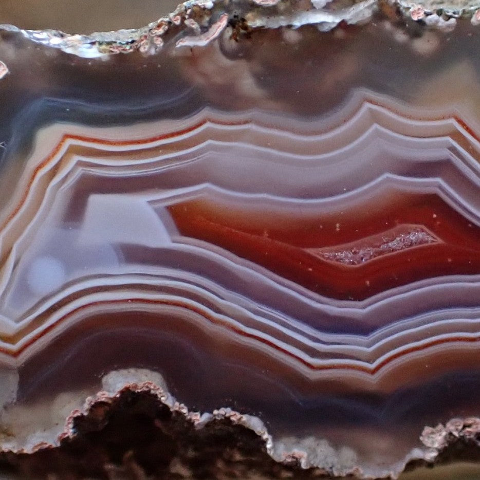 Close-up of Ngabu Malawi agate face revealing fine multi-layered fortification bands, floating sard-carnelian parallax centre and subtle shadow banding — SKU 000474