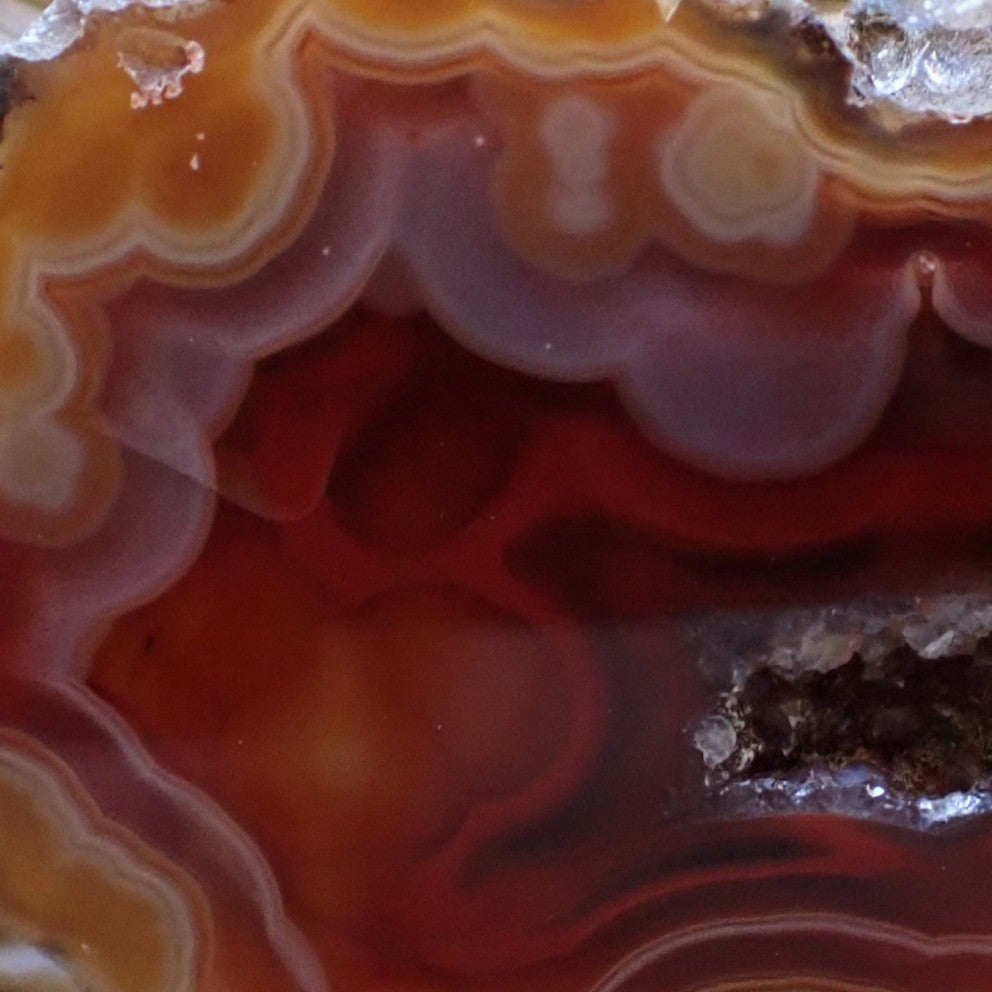Close-up of Malawi agate 54 mm face – amber-orange to carnelian-red chromatism, shadow banding and open vug cavity