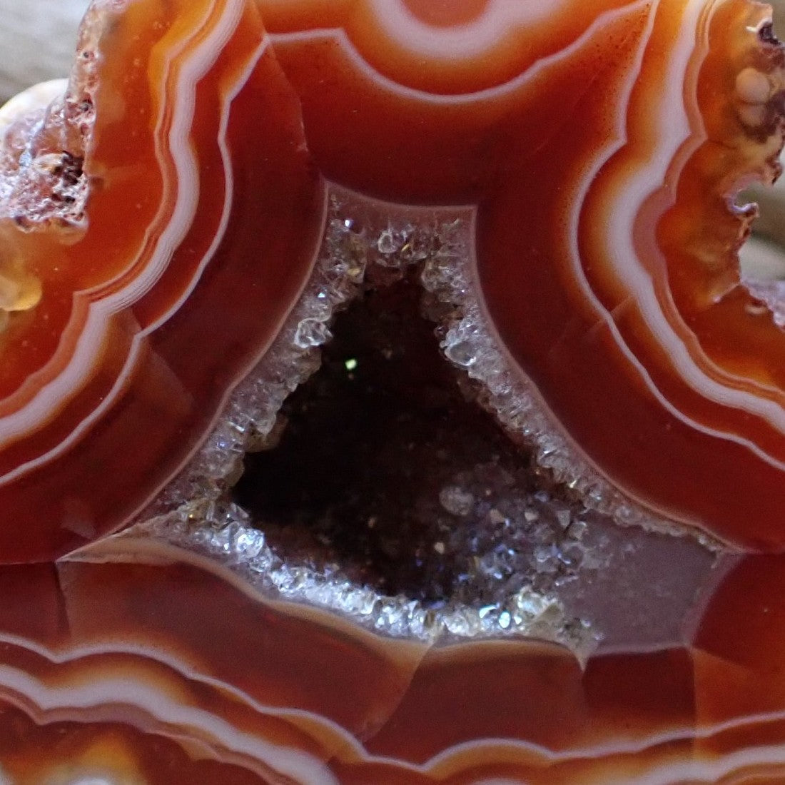 Close-up of Malawi agate 44 mm – triangular druzy vug with white quartz collar and dark interior, sard-carnelian banding detail | SKU 000477