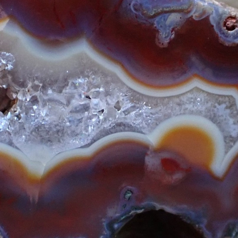 Close-up of Malawi agate 51 mm – macro-crystalline quartz vug with amber accent, scalloped band edges, blue-grey band and ghost banding detail | SKU 000480