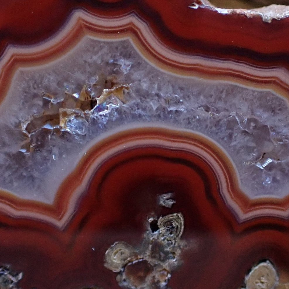 Close-up of Malawi agate 40 mm face – crystalline centre with small vug, scalloped banding, chromatism across banding layers, Ngabu, Malawi | SKU 000483