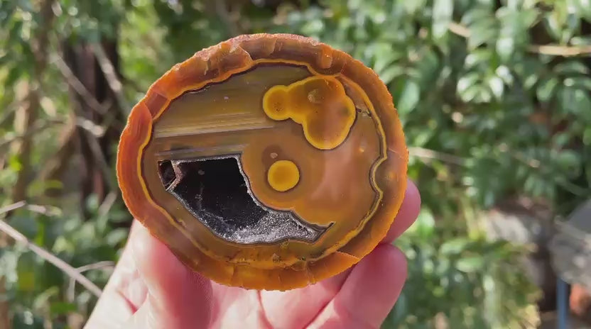 Lilangabi agate 66 mm – video, agate eyes, waterlines, goethite needles in vug, fiery amber-orange palette